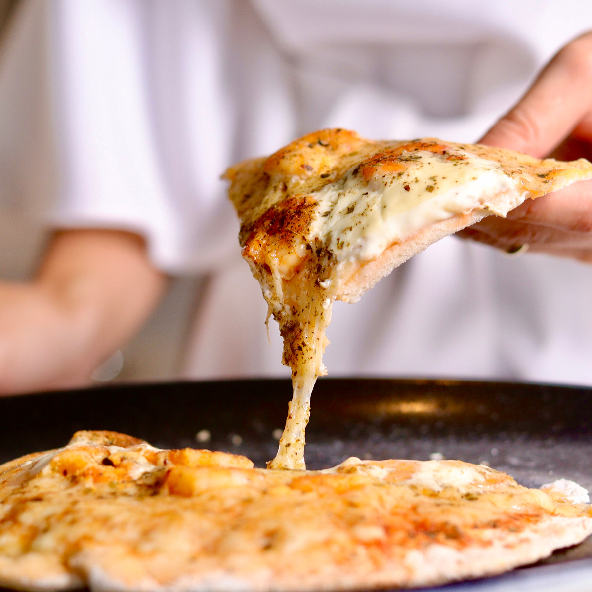 Close-Up Shot of a Person Holding a Slice of Pizza
